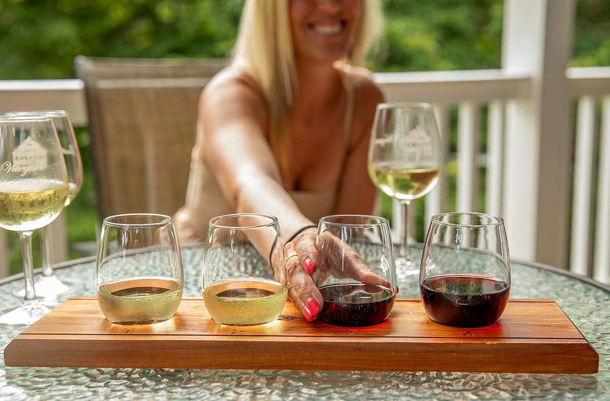 Woman smiling as she grabs a glass from a wine flight at Gauthier Vineyard